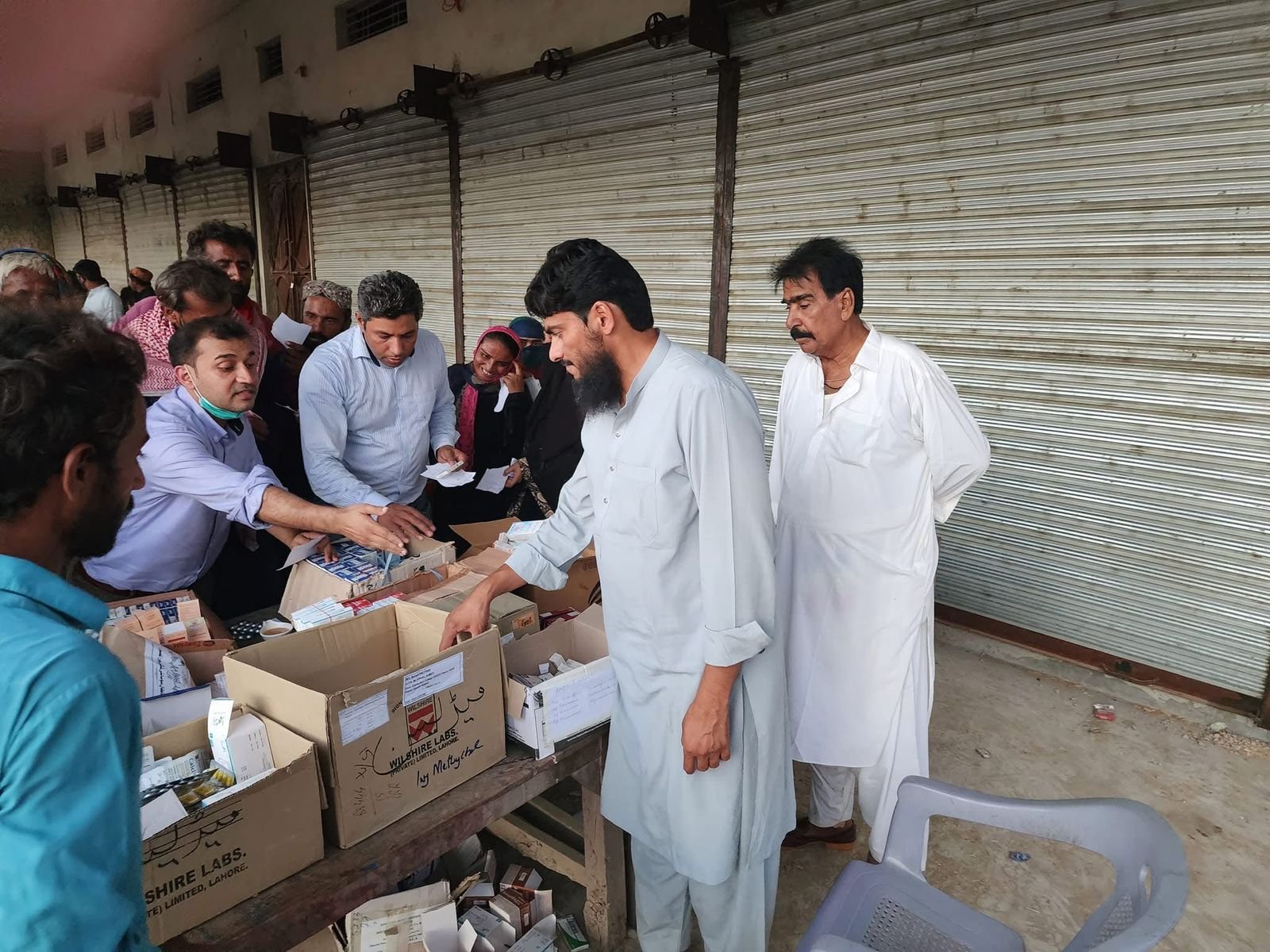 Muslim Medical Mission doctors providing free consultations and medicine at a rural outpatient medical camp with official banner