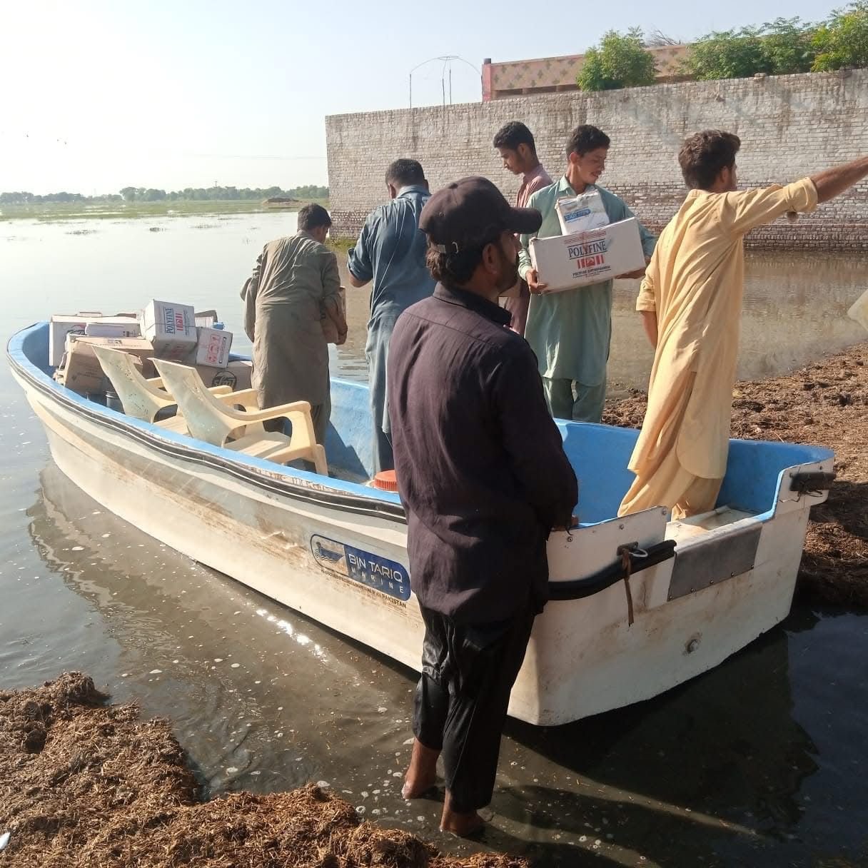 Muslim Medical Mission emergency rapid response team navigating flood waters with banner on rescue boat